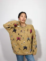 Sweater tejido color mostaza con cuello redondo y diseño bordado a mano con lana merino, con motivos de insectos de diversos colores.