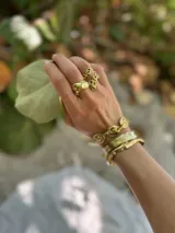 Pulsera tipo esclava abierta, con acabado rústico y textura irregular, en tono plateado. Se vende por unidad.