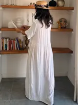 Vestido largo blanco de manga corta, con escote en V y detalles de bordado en el pecho y a lo largo del frente. El tejido es ligero y con caída.