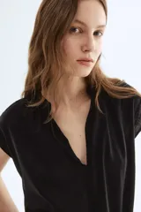 Blusa negra de corte holgado en tejido liviano de algodón y viscosa. Modelo de manga japonesa con escote en V y cuello mao con frunces adelante y atrás. Bajo redondeado.