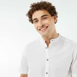 Camisa blanca de lino con cuello mao, manga corta con dobladillo y cierre frontal con botones.