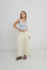 Pantalón 3/4 estilo palazzo confeccionado en denim liviano de tono amarillo pastel, de tiro medio con pliegues delanteros, bolsillos delanteros y traseros aplicados, con detalle de logo metálico PEACH en la parte posterior.