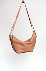 Cartera bandolera marrón de cuero, con correa regulable con hebillas, bolsillo interior y cierre metálico.