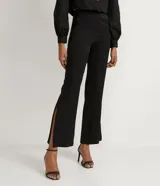 Pantalón flare negro confeccionado en viscosa, con botón en forma de corazón y abertura en los laterales.