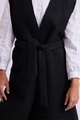 Chaleco largo negro de tejido bouclé, sin mangas y con corte recto.
