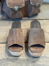 Zuecos con plataforma de madera y capellada marrón con textura croco y tachas doradas.