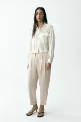 Camisa blanca a rayas verticales color beige, de corte recto, con cuello solapa, manga larga y dos bolsillos de parche en el pecho.
