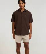 Bermuda de microfibra color beige, con cintura elástica y cordón ajustable. Presenta textura en el tejido y un bolsillo lateral.