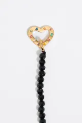 Collar de cuentas de cristal facetado color negro, con cierre de mosquetón dorado y dije de corazón dorado.