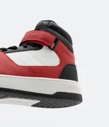 Championes de caña alta, color blanco, rojo y negro, con ajuste de cordones y velcro. Suela bicolor y puntera redondeada.