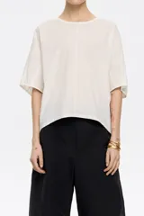 Camiseta blanca de manga corta con cuello redondo, corte holgado y apliques de pequeñas perlas en la parte delantera.