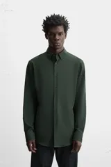 Camisa de vestir verde oscuro, corte slim fit, con cuello italiano, mangas largas con puños abotonados y cierre frontal con botones.