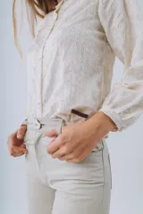 Camisa color crema con bordado floral, cuello mao y mangas largas abullonadas. Cierre frontal con botones.