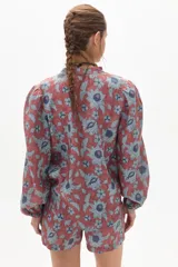 Camisa de lino color ladrillo con estampado de flores azules, cuello mao, mangas largas abullonadas con puño elástico y corte holgado.