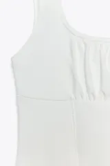 Top blanco de algodón con escote redondo, tirantes anchos y detalle de picueta a tono.