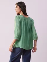 Blusa verde agua de gasa con cuello redondo y aplique de crochet. Tiene mangas 3/4 amplias con puño y botón, y forro interno a tono.