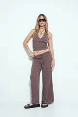 Pantalón de tiro bajo, calce relajado y pierna amplia, color marrón oscuro con textura acanalada. Presenta cintura ajustable con lazo.