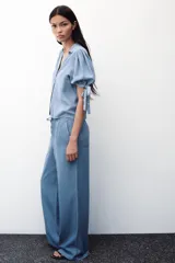 Pantalón celeste de tiro alto con cintura elástica ajustable con cordones, bolsillos delanteros y traseros, y pernera ancha.