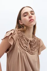 Blusa blanca de lyocell y algodón, con escote fruncido con volados y lazos.