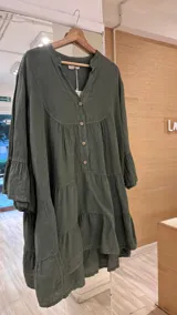 Vestido corto color gris claro, de lino, con botones de coco, corte amplio y mangas largas acampanadas.