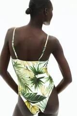 Traje de baño entero con estampado de hojas y flores amarillas, escote en V, breteles finos ajustables, copas con relleno extraíble, detalle fruncido en el busto y abertura cut-out en la cintura.