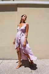 Vestido largo blanco de crepé con escote en V, breteles finos y corte envolvente con volados en el ruedo.