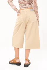 Bermuda de jean color beige, tiro medio, con bolsillos delanteros y traseros.