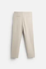 Pantalón de jogging color beige confeccionado en tejido de mezcla de algodón. Cuenta con cintura elástica ajustable con cordón, bolsillos frontales y traseros.