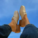 Zuecos color crema con punta cuadrada, detalle de nudo en el empeine y taco de madera.