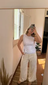 Top blanco sin mangas, confeccionado en crepe brilloso, con cierre en la parte trasera y tiras para atar en la delantera.