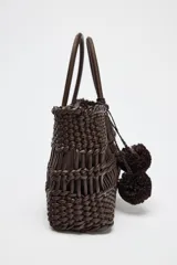 Bolso de mano marrón con cuerpo trenzado y doble asa. Incluye charm extraíble y bolsa interior con cierre fruncido.