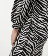 Blusa de viscosa con estampado animal print en blanco y negro, escote en V, mangas largas abullonadas con puños ajustados y dobladillo mullet.