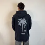 Canguro negro con capucha y cordones ajustables. Estampado en la espalda con una palmera gris, logo de la marca y texto.