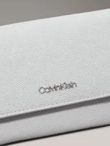 Billetera de plegado triple Calvin Klein, color blanco o gris muy claro, con textura de monograma en relieve y logo metálico plateado en el frente.