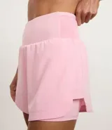 Bermuda deportiva femenina de microfibra color amarillo claro, con diseño de doble capa: un short interno ajustado y una capa externa suelta con bajo redondeado. Posee cintura alta.