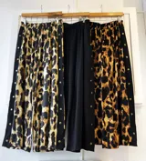 Pantalón palazzo negro con cintura elastizada y botones dorados decorativos en los laterales.