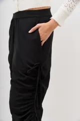 Pantalón jogger negro de nylon con elástico ancho en la cintura, puños elásticos ajustables y lazos laterales para fruncir.