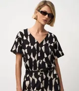 Blusa de manga corta con escote en V y un estampado geométrico abstracto en blanco y negro.