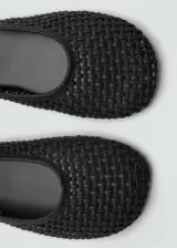 Zapato bajo negro con efecto piel trenzada, punta redonda y cierre de tira con hebilla.