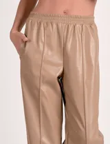 Pantalón de eco cuero color marrón, marca Elan, con pretina elastizada, bolsillos delanteros, pierna recta y costura frontal.
