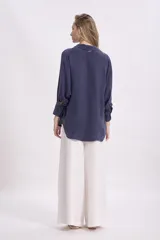 Camisa color verde oliva, de corte recto, con cuello camisero y mangas largas con puños abotonados.