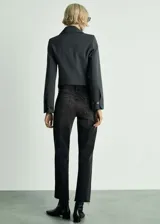 Pantalón de jean negro con lavado gastado, corte recto, tiro medio y terminación desflecada.