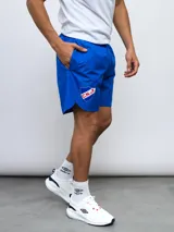 Short deportivo azul con escudo del Club Nacional de Football en la pierna derecha y detalles tricolor.
