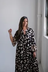 Vestido largo de corte amplio con estampado animal print en tonos negro y beige, cuello camisero y mangas largas.
