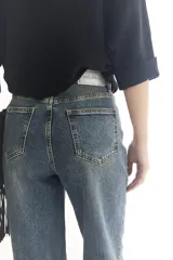 Pantalón de jean celeste con corte recto, tiro alto y dobladillo en color beige.