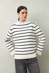 Sweater de punto a rayas horizontales color beige y blanco, con cuello bote y corte holgado.