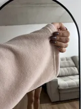 Sweater rosa de tejido de punto acanalado, con cuello alto y mangas anchas.