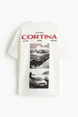 Remera blanca de algodón con corte oversized, cuello redondo y estampado frontal con texto en color rojo.