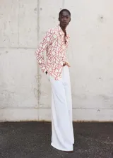 Camisa de manga larga color blanco con estampado abstracto en color ladrillo, cuello camisero y cierre frontal con botones ocultos.