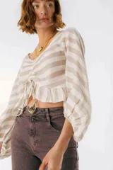 Blusa blanca de lino con escote en V, mangas largas abullonadas y frunce central.